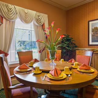 An elegantly set dining room table with a floral centerpiece and warm-toned decor.
