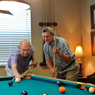 Two men enjoying a game of billiards indoors.