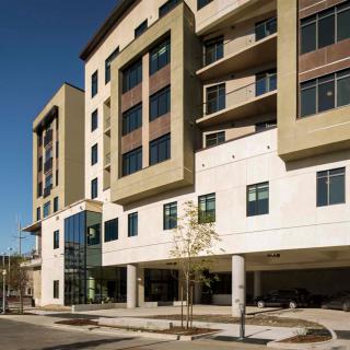 A modern apartment building with a multi-story design and large windows.