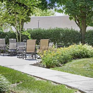 A tranquil garden scene with outdoor seating and lush greenery.
