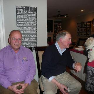 Two men seated indoors with a dog.