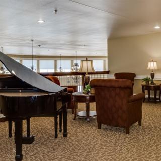 A cozy lounge area featuring a grand piano and comfortable seating.
