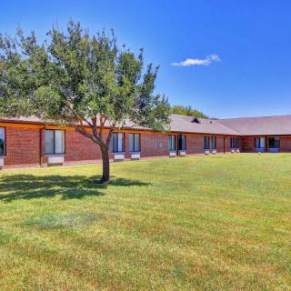 A brick building with a tree and expansive lawn under a clear blue sky.