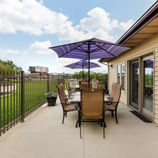 A cozy outdoor patio with a dining set and umbrellas under a clear sky.
