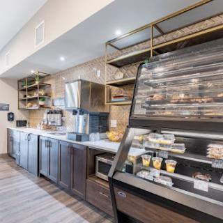 A modern cafe kitchen featuring a sleek bakery display and a coffee station, designed for efficiency and style.