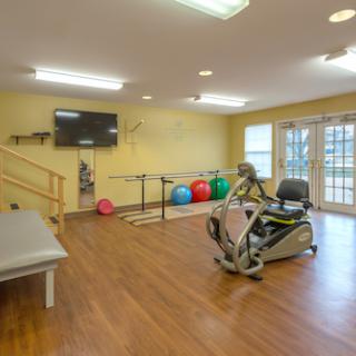 A well-equipped fitness space featuring a recumbent bike, exercise balls, and ample natural light.