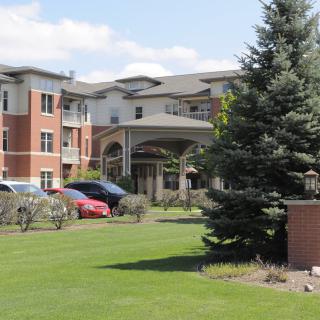 A modern residential building with well-maintained landscaping and parked cars.