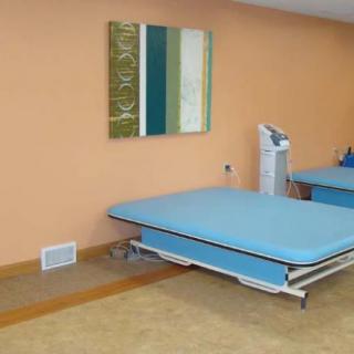 A physical therapy room with a treatment table and equipment.