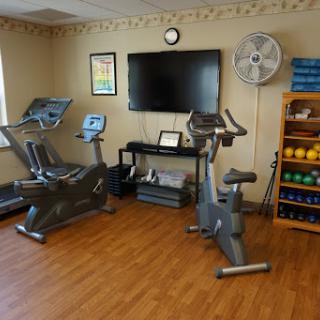 A well-equipped workout space featuring an elliptical machine, a stationary bike, and various exercise accessories.