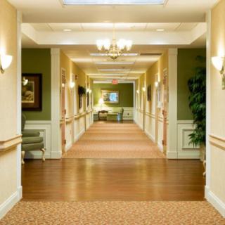 A well-lit hallway with warm colors and decor, typical of a nursing home setting.