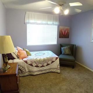 A cozy bedroom with a single bed, armchair, and decorative elements.