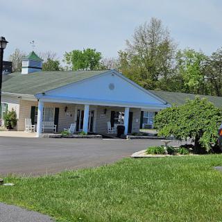 A view of a motel with a blue facade surrounded by lush greenery.