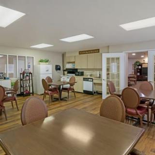 A cozy dining area with multiple tables and chairs, adjacent to a small kitchen.