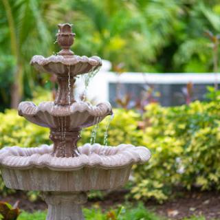 A beautiful stone fountain surrounded by lush greenery in a serene garden setting.