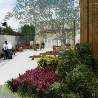 A serene outdoor garden with lush plants, benches, and a paved pathway.