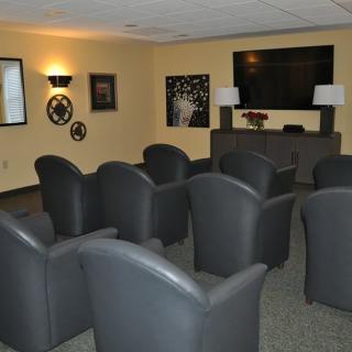 A cozy home theater room with rows of comfortable seating facing a large television screen.