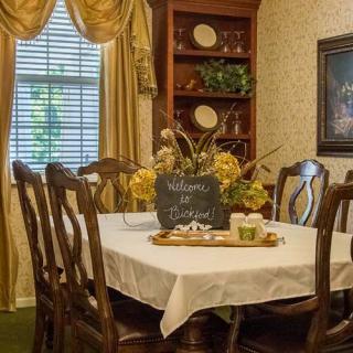 A cozy dining room with a table set for gathering, adorned with flowers and elegant decor.