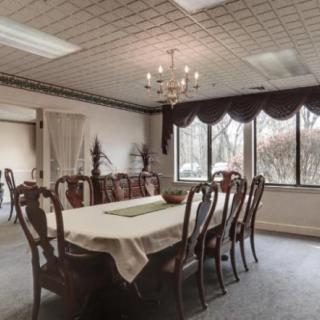A spacious dining room with a large table, elegant chairs, and a chandelier.