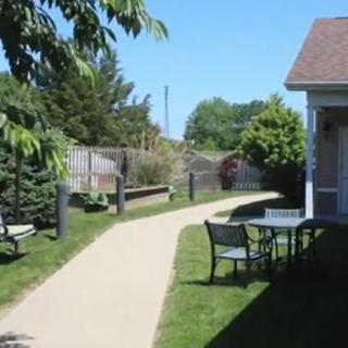 A serene backyard with a paved pathway, outdoor seating, and lush greenery.