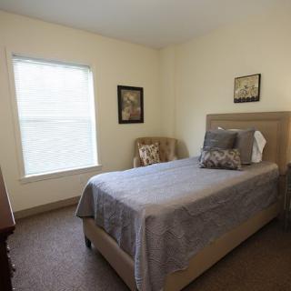 A minimalist bedroom with a single bed, chair, and window.