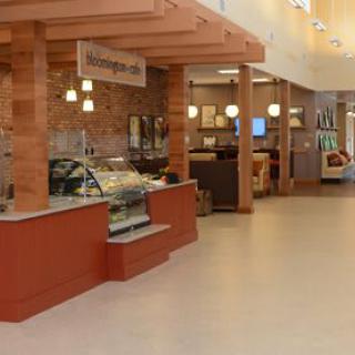 A cozy caf with a counter and display case, featuring a seating area and warm lighting.