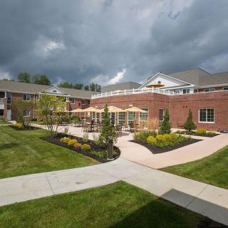 A courtyard with well-maintained landscaping, surrounded by a brick building under an overcast sky.