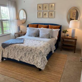 A cozy, well-decorated bedroom with a neatly made bed, nightstands, and stylish lighting.