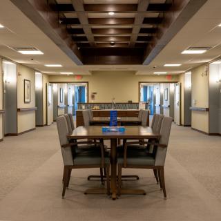 A well-lit, elegantly furnished dining area with a table and chairs in a hallway setting.