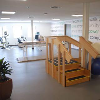 A spacious rehabilitation center equipped with exercise machines and a small staircase for physical therapy exercises.