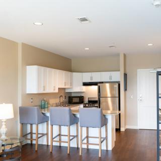 Modern apartment kitchen with stainless steel appliances and a breakfast bar with seating.