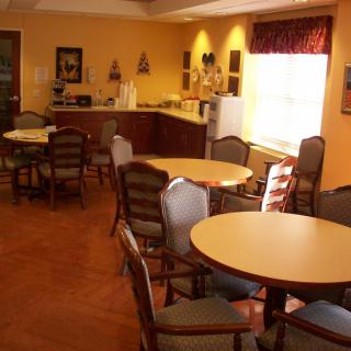 A cozy dining room with several tables and chairs, featuring a kitchen area in the background.