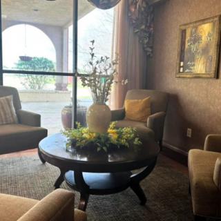 A cozy living room with comfortable chairs and a decorated coffee table near a large window.