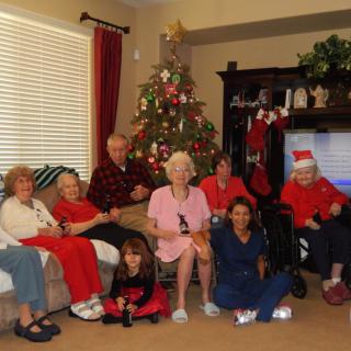 A family gathered in a living room celebrating Christmas with a decorated tree and stockings.