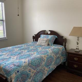 A cozy bedroom with a bed, nightstand, and lamp.
