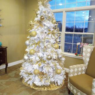 A beautifully decorated white Christmas tree adorned with gold ornaments, creating a warm and festive ambiance.