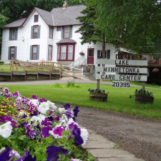 A historic building surrounded by a vibrant summer garden with a sign in front.