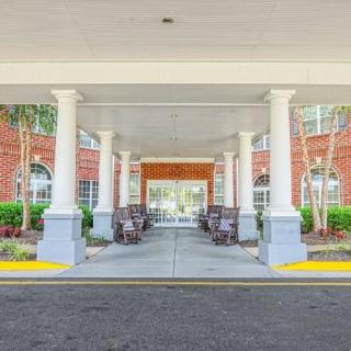 The entrance to a building with a covered walkway, featuring columns and benches.