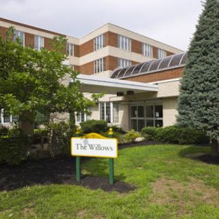 The exterior of a facility named 'The Willows', featuring landscaped grounds and modern architecture.