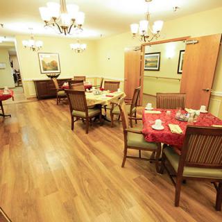 A cozy dining area with neatly arranged tables and chairs, illuminated by elegant chandeliers.