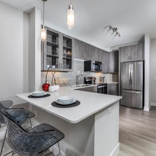 A modern kitchen with sleek appliances, an island, and stylish seating.