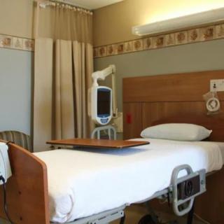 A hospital room with a neatly made bed and medical equipment.