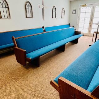 Interior view of a church with blue upholstered pews.