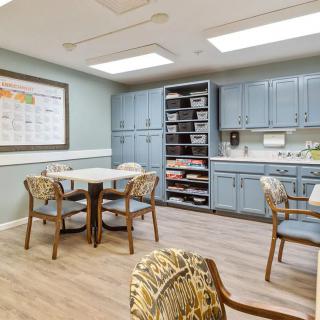 A cozy kitchen and dining area with light blue cabinets, a table, and chairs.