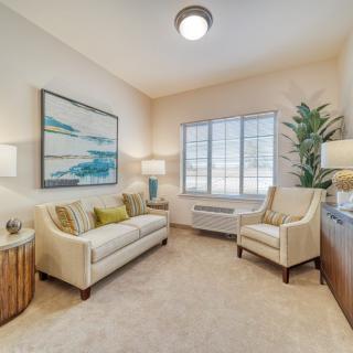 A cozy living room with neutral decor, featuring a sofa, chairs, and soft lighting.