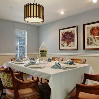 A stylish dining room with a neatly arranged table setting and elegant artwork on the walls.