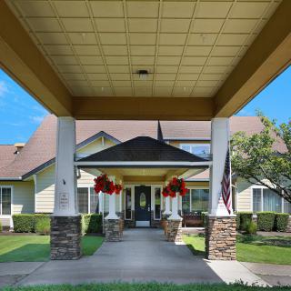 A view of a residential building with a covered entrance and landscaped surroundings.