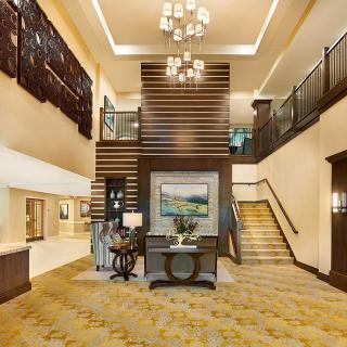 A modern hotel lobby featuring elegant interior design with a prominent staircase and chandelier.