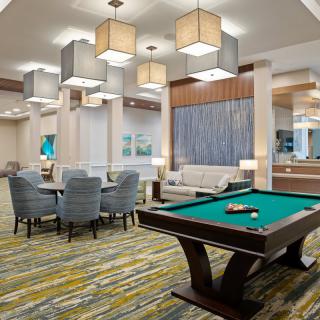 A stylish lounge area featuring a billiards table, upholstered chairs, and modern lighting.
