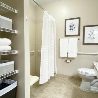 A modern bathroom with a shower, toilet, and neatly arranged towels.