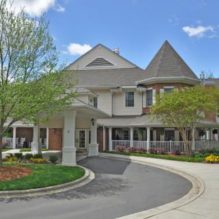 A picturesque residential building with a circular driveway and well-maintained landscaping.